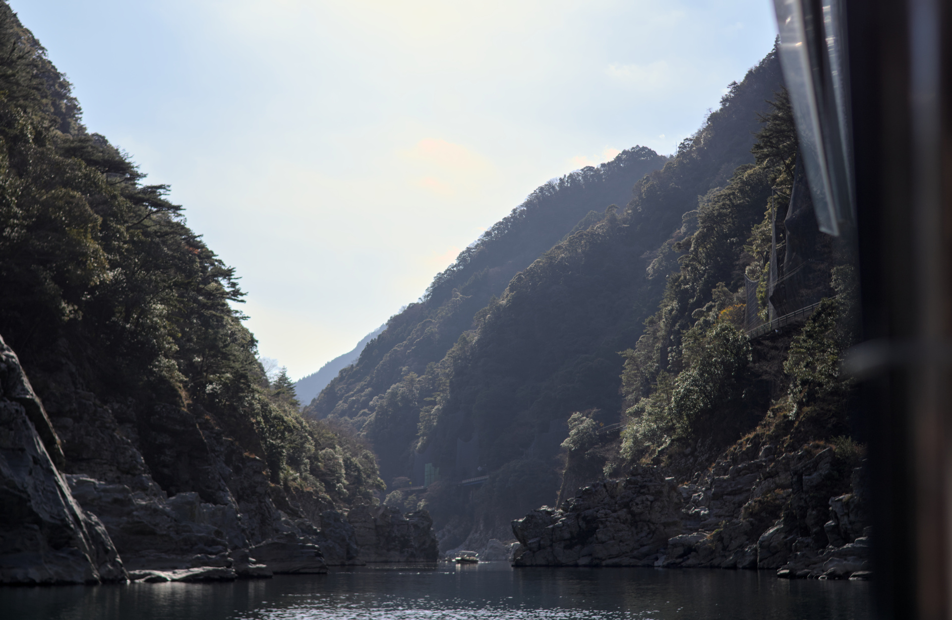 View of a valley from its bottom, water at its base and tall mountains on its sides.